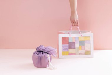 hold a traditional patterned shopping bag next to a gift cloth clipart