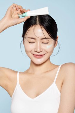 Asian Woman Poses With Cream Around Her Eyes clipart
