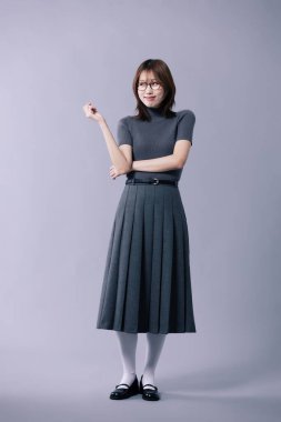 A Korean woman in her 20s wearing glasses and a gray knit short sleeved shirt and pleated skirt clipart