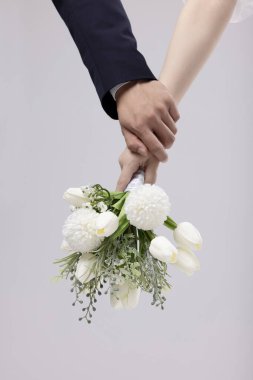 Newlyweds' hands holding a bouquet clipart