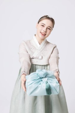 Western woman wearing Hanbok and holding a gift wrapped in Korean style clipart