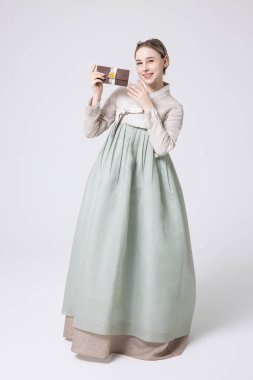 A foreign woman wearing traditional Korean hanbok holding a holiday gift clipart