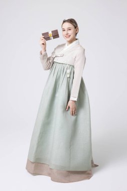 A foreign woman wearing traditional Korean hanbok holding a holiday gift clipart