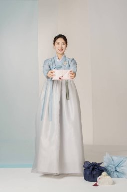 Portrait of a beautiful woman standing holding a holiday gift wearing an elegant and elegant hanbok clipart