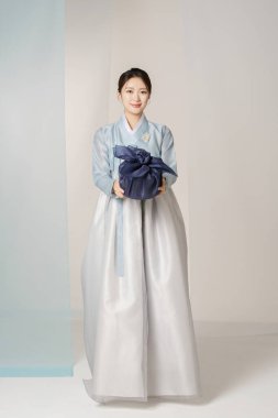 Portrait of a beautiful woman standing holding a holiday gift wearing an elegant and elegant hanbok clipart