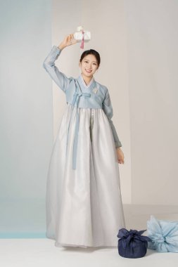 Portrait of a beautiful woman standing holding a holiday gift wearing an elegant and elegant hanbok clipart