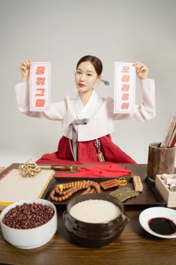 A shaman sitting wearing a hanbok and holding an amulet clipart