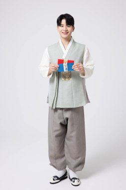 Portrait of a young man wearing hanbok and holding a luxury gift certificate clipart