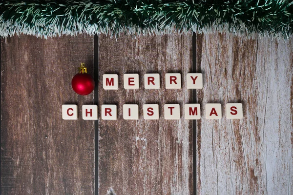 stock image Merry Christmas written with letters of a game and Christmas ornaments on a wooden background