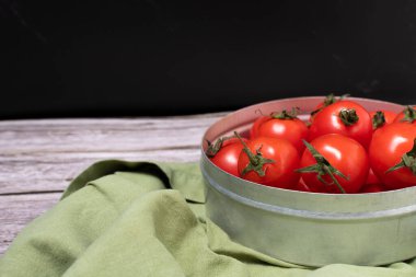 Side view of a set of cherry tomatoes in metal container with green cloth.