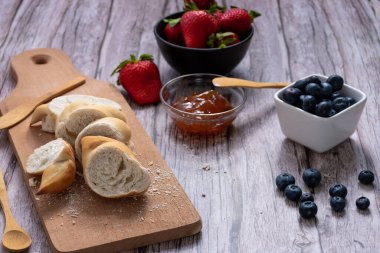 Yabanmersini, çilek, tutkulu meyve reçeli, ekmek tahtası ve ahşap çatal bıçaklı kaplar..