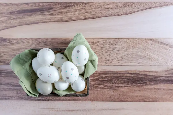 Decorated Easter eggs in a basket on a wooden background.
