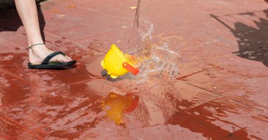 Sarı kova düşüyor ve su sıçrıyor, bir çocuk fırlatıyor..