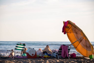 Sahildeki plaj eşyaları: şemsiye, konserve kutuları, sandalyeler, ayakkabılar, vs..