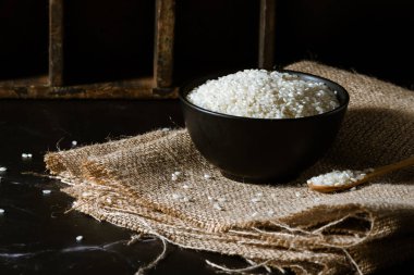 Siyah kase ve çiğ beyaz yamani pilavlı tahta kaşık..