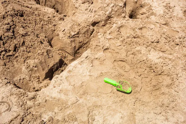 海滩上沙滩上的绿色塑料玩具铲子 — 图库照片