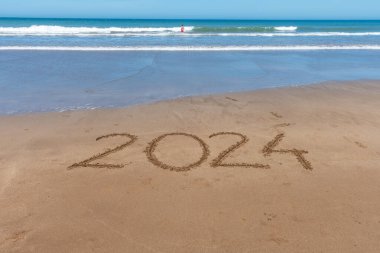 2024, dalganın gelişiyle birlikte deniz kıyısındaki kumda yazılmış..