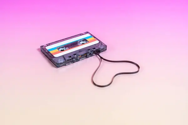 Transparent audio cassette with labels and heart-shaped tape on the outside.