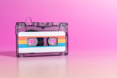 Fuşya arka planında etiketleri olan şeffaf ses kaseti.
