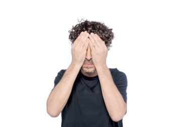 Orta yaşlı bir adam beyaz arka planda elleriyle gözlerini kapatıyor..