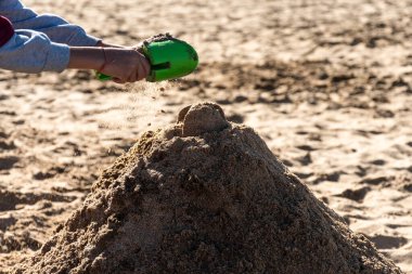 Kumsalda kum dağı yapan bir çocuğun elleri..