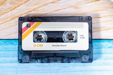 Renkli ahşap arka planda bir müzik kasetinin üst görüntüsü.