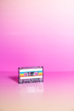Fuşya arka planında etiketleri olan şeffaf ses kaseti.