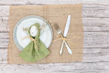 Peçeteli bir tabak, süslü Paskalya yumurtası ve çatal bıçak takımı..