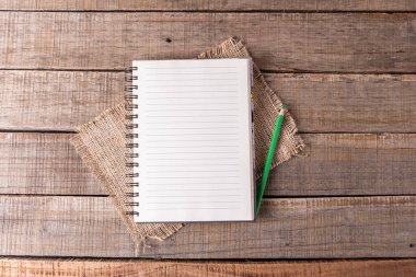 Astarlı sayfaları olan sarmal defter ve kırsal ahşap üzerine yeşil bir kalem..