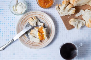 Ekmek, reçel, krem peynir ve kahveli bir kahvaltı manzarası..