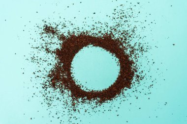 Turkuaz arka planda dairesel silueti kesen öğütülmüş kahve tozu.