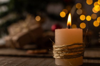 Noel süsleme mumu yakıldı, arka planda ağaç ve hediyeler var..