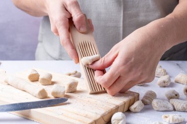 İnsan elleri gnocchi 'yi ahşap bir aletle şekillendiriyor..