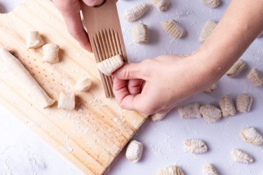 Gnocchi 'yi ahşap bir aletle şekillendiren insan ellerinin yakın plan detayları..