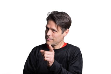 Orta yaşlı bir adam beyaz arka planda kameraya işaret ediyor..