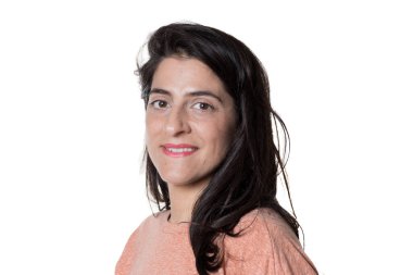 Sıradan giyinmiş bir kadın beyaz arka planda kameraya bakıyor..