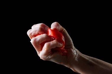 Siyah bir arkaplan önünde sıkıca domates sıkıyorum..