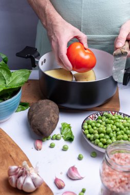 Pişirmek için diğer sebzeler arasında yuvarlak kırmızı domates almak.