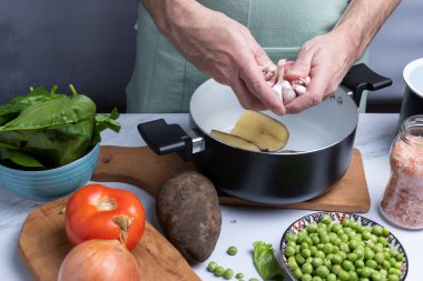 Yemek yapmak için diğer sebzelerin arasına sarımsak götürüyor..