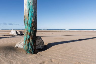 Seçici bir şekilde bir kütüğe ve deniz kenarındaki bazı taşlara odaklanmış rahatlatıcı ve rahatlatıcı bir sahne..
