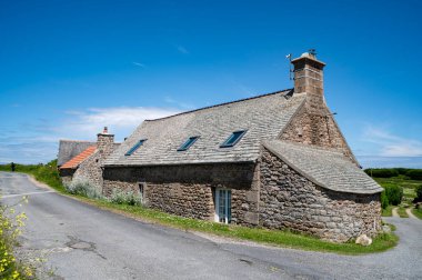 Fransa 'nın Cherbourg bölgesindeki Cape Levi' ye giden yolun kenarındaki Norman evi. Tahta levhayla kaplı granit taş yapı. Baca binanın kenarlarından birine entegre edilmiş..