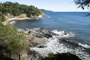 Mart ayında Akdeniz kıyılarının öğleden sonra manzarası. Kıyı yolu kayaların arasındaki sarp kıyı boyunca uzanıyor..