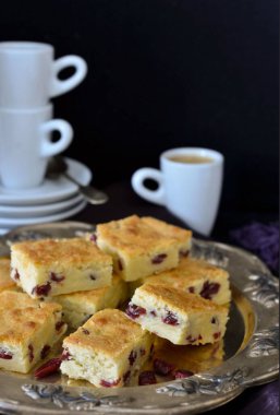 Dekoratif bir tabakta kızılcık saadeti çubukları ve arka planda bir yığın beyaz fincan ve tabaklar..