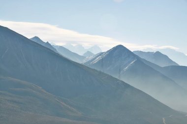Karla kaplı dağ zirveleri bulutlu gökyüzünü delip geçer. Alp kış manzarası.