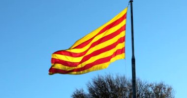 Büyük kırmızı ve sarı Katalonya bayrağı mavi arka planda rüzgarda dalgalanıyor. Görüntüyü Kapat - DCi 4K Çözünürlüğü