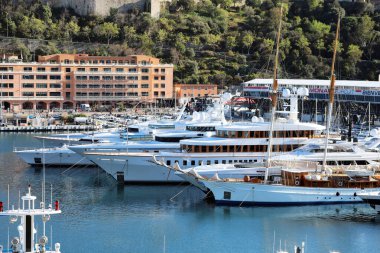 Monte-Carlo, Monaco - 16 Nisan 2023: Dünyanın en büyük ve en pahalı yatları Monte-Carlo, Monaco limanında sıkıca doldurulmuş, Formula 1 Grand Prix tesisleri arka planda