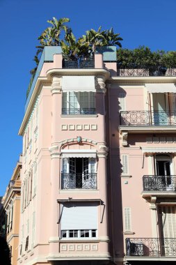 Monte-Carlo, Monaco - 16 Nisan 2023: Monte Carlo, Monaco 'da büyüleyici, küçük, pembe bir vintage tarzı bina, içinde muz ağaçları olan bir çatı bahçesi ve süslü bir ön cephe yer alıyor. 