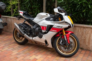 Monte-Carlo, Monaco - 9 Haziran 2024: Bir Yamaha R1 spor motosikleti tuğla kaldırıma park edilmiş. Motosiklet, performansını ve mühendisliğinin mükemmelliğini vurgulayan beyaz ve kırmızı renk şemasına sahip parlak bir tasarıma sahiptir.