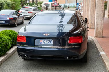 Monte-Carlo, Monaco - 9 Haziran 2024: lüks bir caddeye park edilmiş şık bir Bentley Uçan Spur lüks sedan. Zarif siyah araç zarif tasarımı ve yüksek kalitede cazibesini sergiliyor, varlıklı ortama kusursuz bir şekilde uyum sağlıyor.