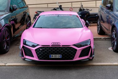 Monte-Carlo, Monaco - 9 Haziran 2024: Hassler Custom tarafından özelleştirilmiş çarpıcı pembe bir Audi R8, lüks bir araba sahasına park edilmiş. Bu yüksek performanslı spor araba diğer lüks araçların yanında canlı rengi ve parlak tasarımıyla göze çarpıyor.